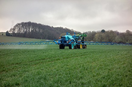Symbolfoto: Traktor mit Anhänger versprüht eine Flüssigkeit auf einem Feld